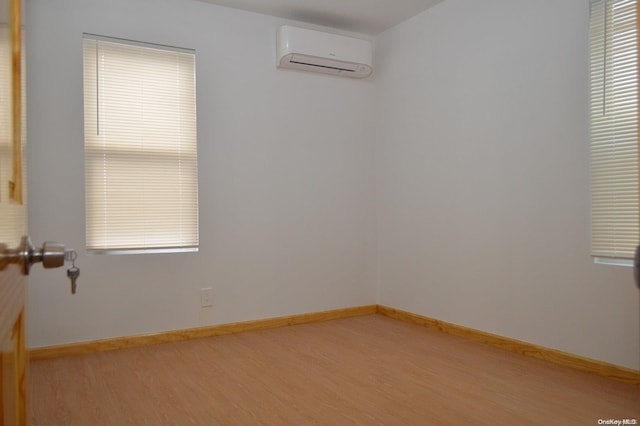 empty room featuring hardwood / wood-style flooring and a wall mounted AC