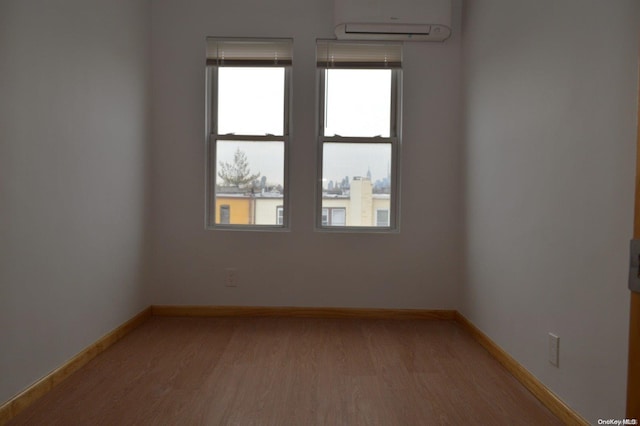 empty room with a wall mounted air conditioner and light wood-type flooring