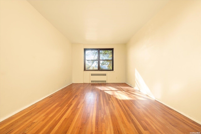 empty room with radiator heating unit and light hardwood / wood-style floors