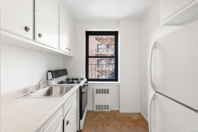 kitchen featuring radiator, sink, stainless steel range with gas cooktop, white refrigerator, and white cabinets