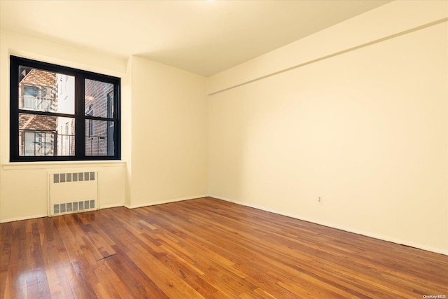 empty room featuring radiator and hardwood / wood-style floors