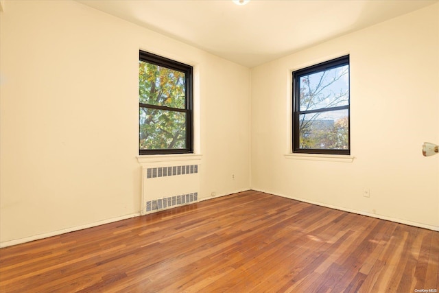 empty room featuring radiator and hardwood / wood-style flooring