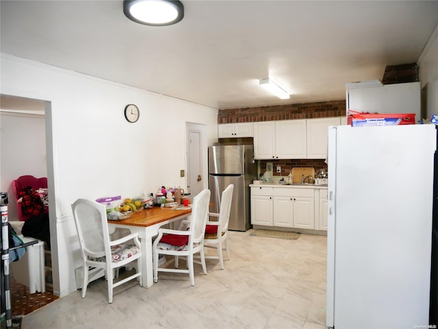 kitchen with decorative backsplash, white fridge, white cabinetry, and stainless steel refrigerator