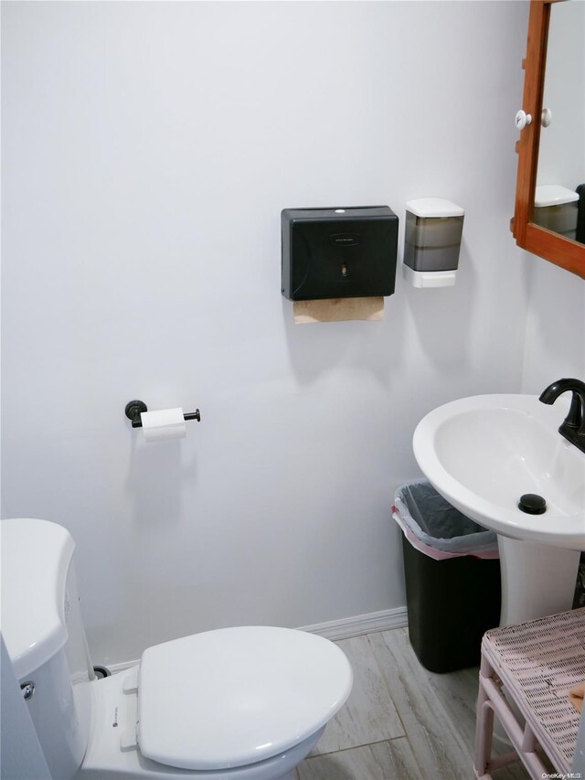 bathroom with toilet, wood-type flooring, and sink