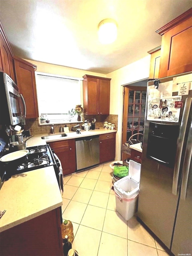 kitchen with decorative backsplash, sink, light tile patterned floors, and appliances with stainless steel finishes