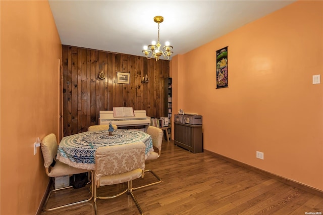 dining room featuring a chandelier, wood-type flooring, and wooden walls