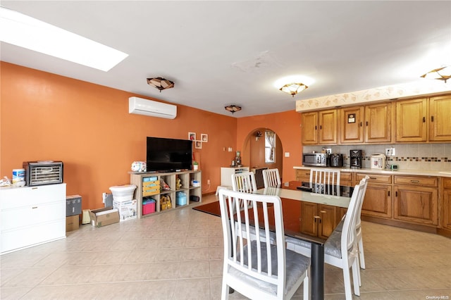 tiled dining room featuring a skylight and a wall mounted AC