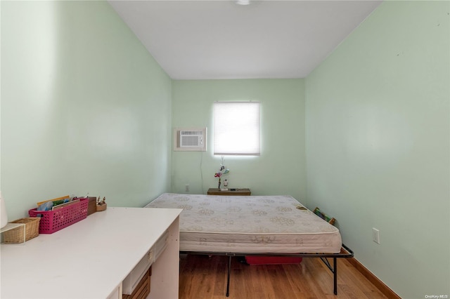 bedroom featuring wood-type flooring and a wall unit AC