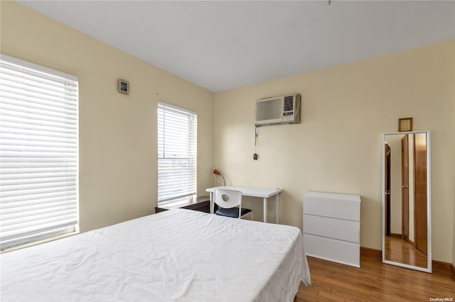 bedroom featuring hardwood / wood-style floors and an AC wall unit