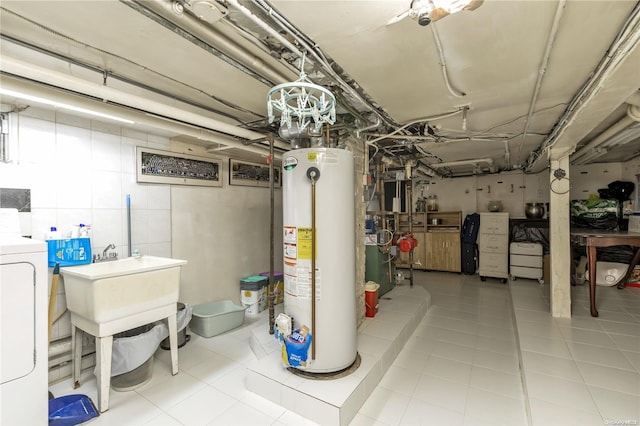 basement featuring light tile patterned flooring, gas water heater, and washer / clothes dryer