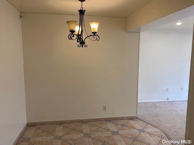 carpeted spare room with a chandelier