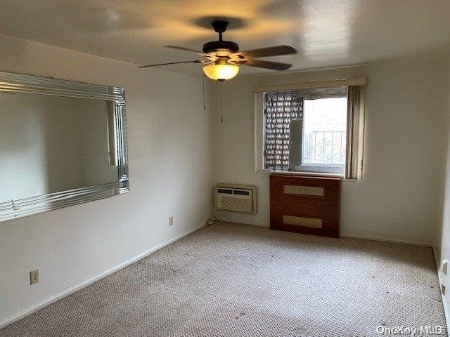 unfurnished room with a wall mounted air conditioner, light colored carpet, and ceiling fan