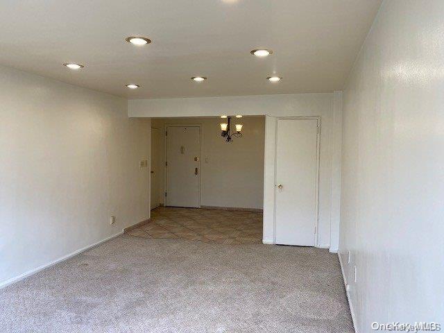 carpeted empty room featuring a notable chandelier