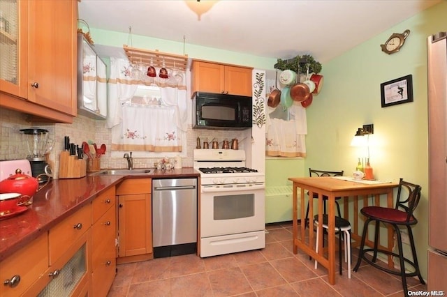 kitchen featuring sink, stainless steel dishwasher, decorative backsplash, light tile patterned floors, and white gas stove