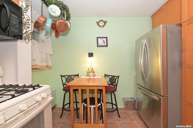 kitchen featuring stainless steel refrigerator, gas range gas stove, and tile patterned flooring