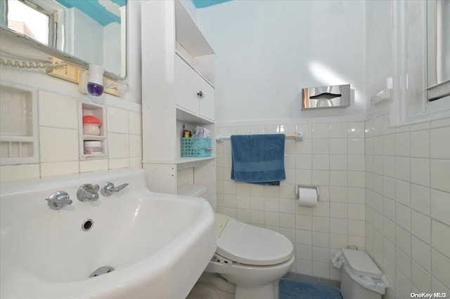 bathroom with toilet, tile walls, and sink