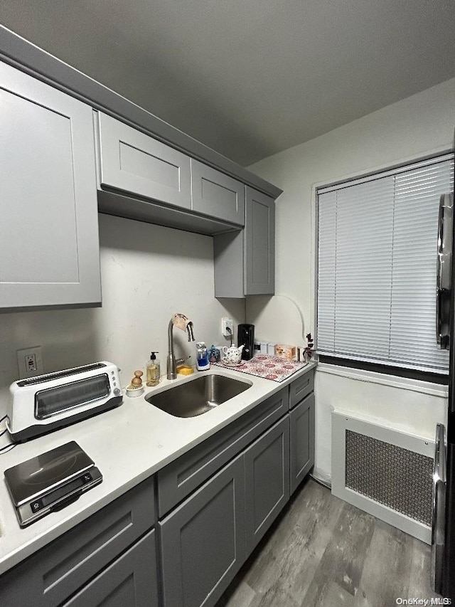 kitchen featuring gray cabinets, sink, dark hardwood / wood-style floors, and radiator