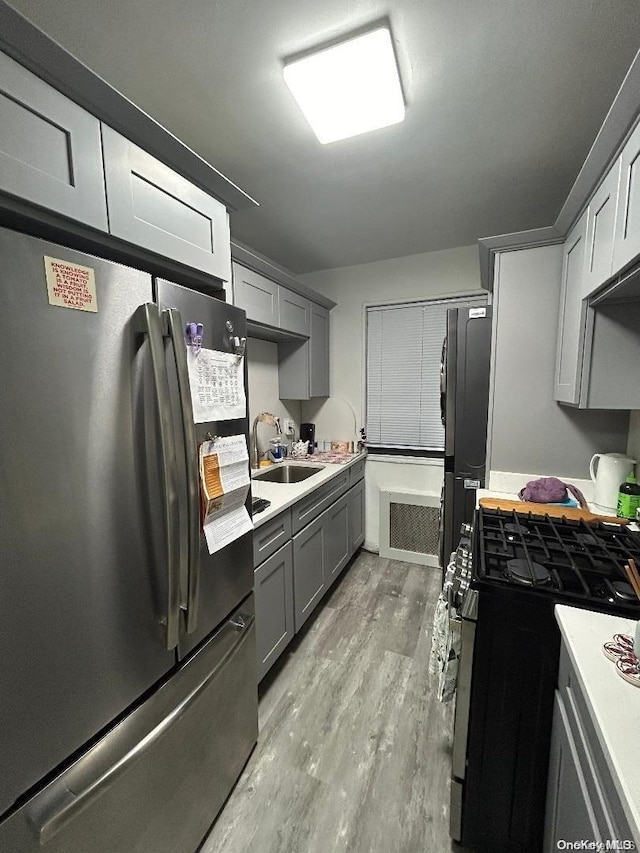 kitchen with stainless steel refrigerator, sink, black range with gas stovetop, light hardwood / wood-style flooring, and refrigerator