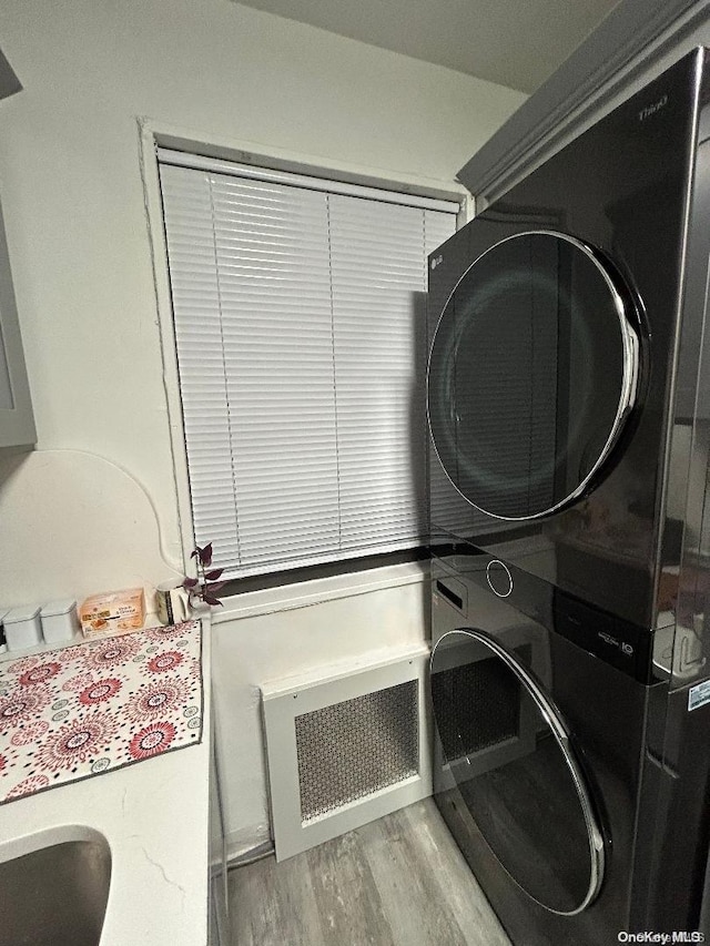 washroom with light hardwood / wood-style floors and stacked washer and clothes dryer