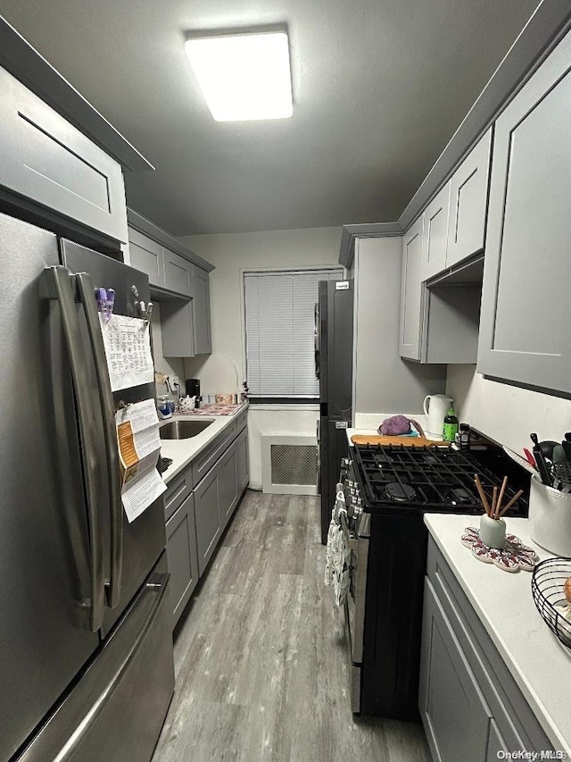 kitchen with gray cabinets, high end stove, fridge, light hardwood / wood-style floors, and stainless steel refrigerator