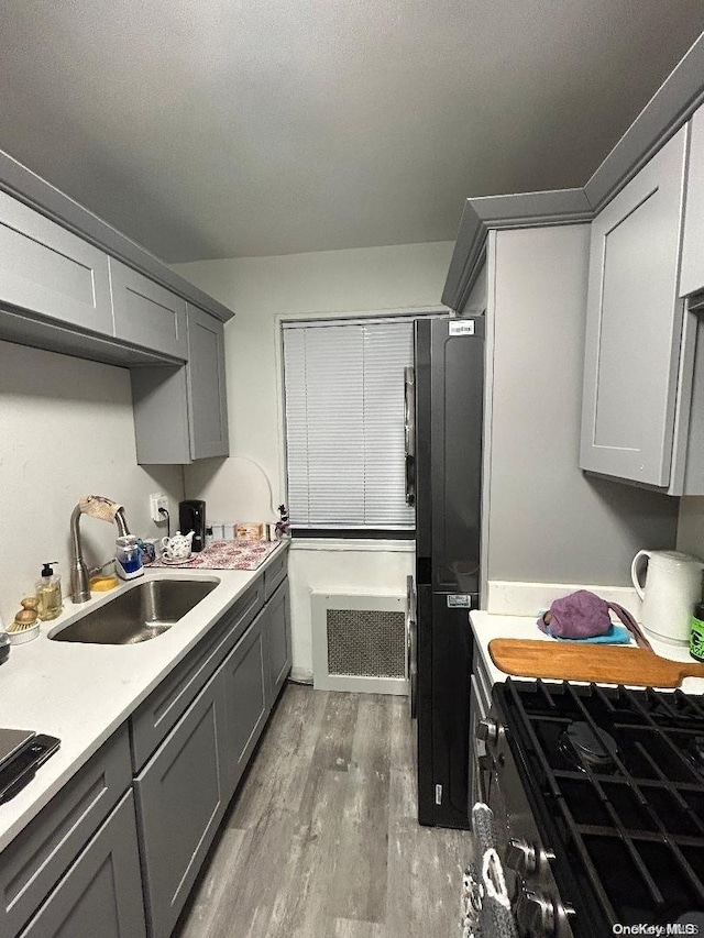 kitchen with dark hardwood / wood-style flooring, sink, gray cabinets, and black stovetop