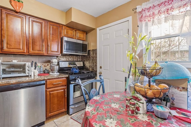 kitchen featuring light tile patterned flooring, stainless steel appliances, and tasteful backsplash