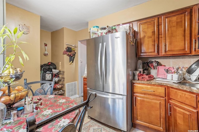 kitchen with decorative backsplash, stainless steel fridge, and light tile patterned floors