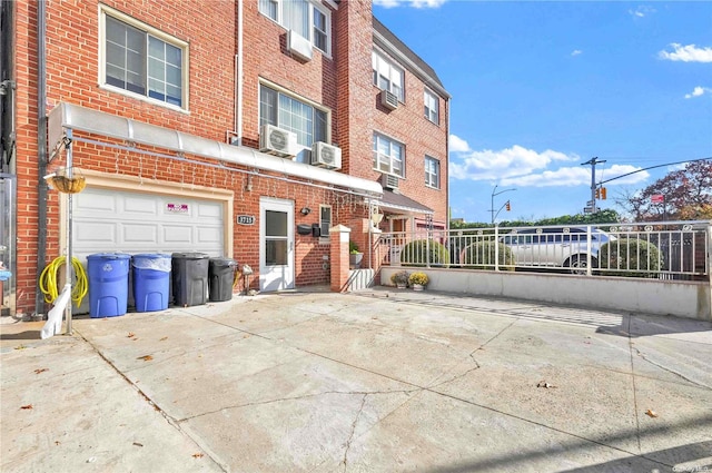 view of property with a garage and a wall unit AC