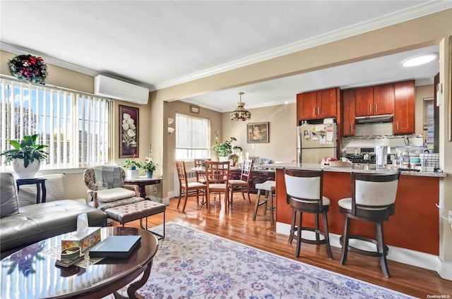 interior space featuring stainless steel fridge, hardwood / wood-style flooring, a wall mounted AC, and ornamental molding