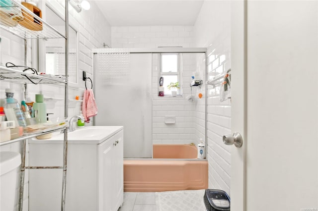 full bathroom with vanity, tile patterned flooring, toilet, enclosed tub / shower combo, and tile walls