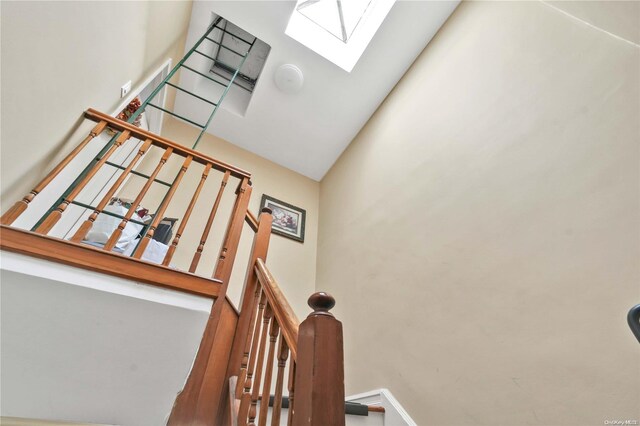 stairs featuring a towering ceiling and a skylight