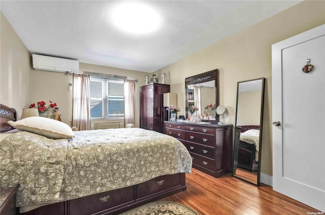 bedroom featuring hardwood / wood-style flooring and an AC wall unit