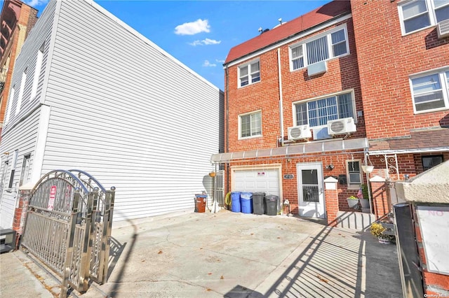 rear view of house with an AC wall unit, cooling unit, and a garage