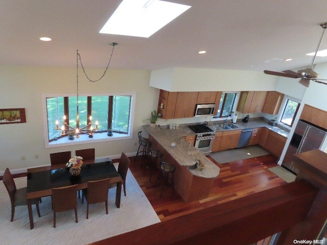 kitchen featuring kitchen peninsula, a wealth of natural light, ceiling fan with notable chandelier, and decorative light fixtures