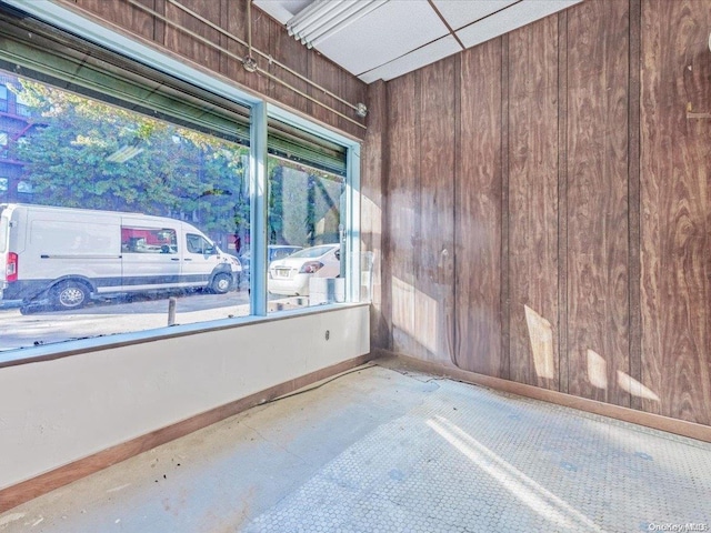 unfurnished room featuring concrete flooring and wooden walls