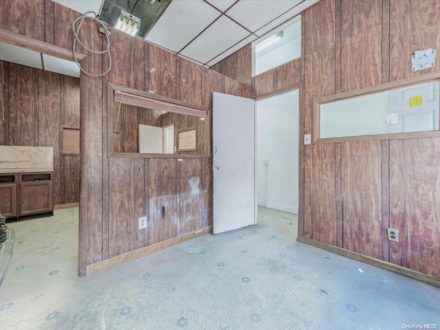 carpeted empty room featuring wooden walls