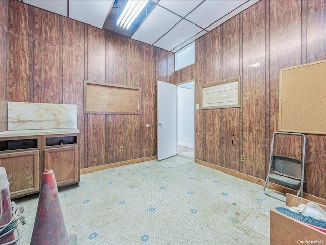 unfurnished office featuring a paneled ceiling, light carpet, and wooden walls