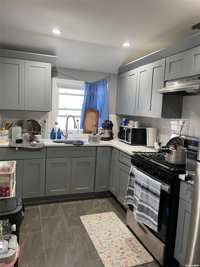 kitchen featuring gray cabinets, decorative backsplash, gas stove, and sink