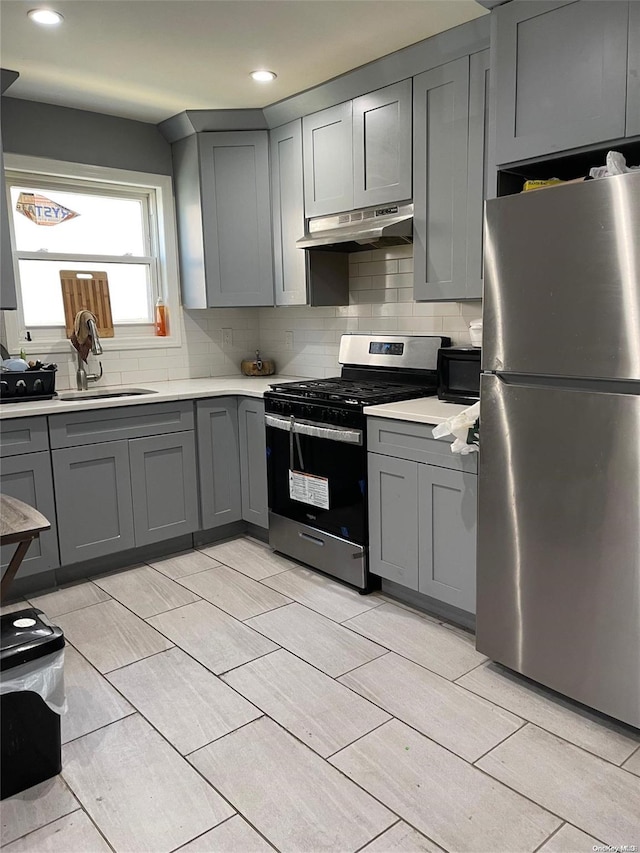 kitchen featuring appliances with stainless steel finishes, gray cabinets, tasteful backsplash, and sink