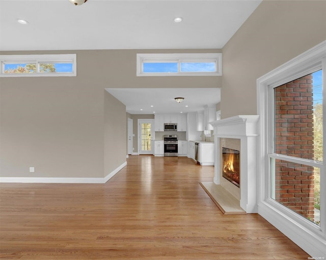 unfurnished living room featuring plenty of natural light and light hardwood / wood-style flooring