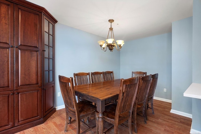 dining space with light hardwood / wood-style flooring and an inviting chandelier