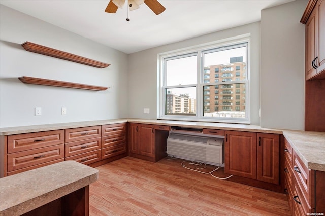 kitchen with light wood-type flooring, ceiling fan, and built in desk