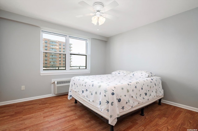 bedroom featuring hardwood / wood-style flooring, ceiling fan, and a wall mounted air conditioner