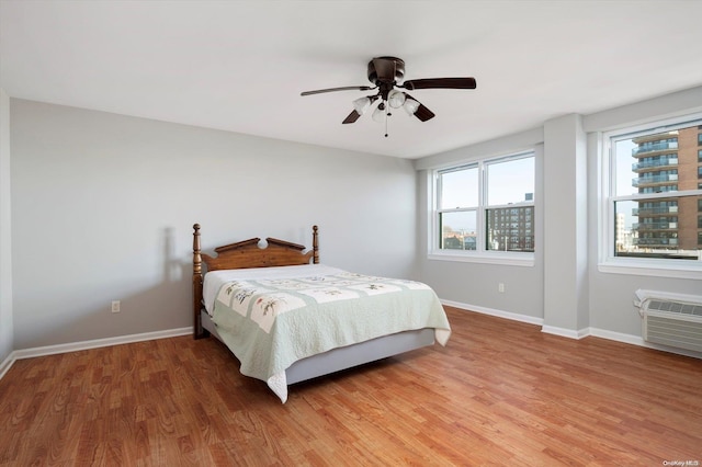 bedroom featuring hardwood / wood-style floors, ceiling fan, and a wall mounted air conditioner