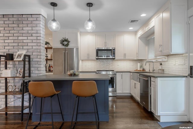 kitchen with decorative backsplash, appliances with stainless steel finishes, dark wood-type flooring, pendant lighting, and white cabinets