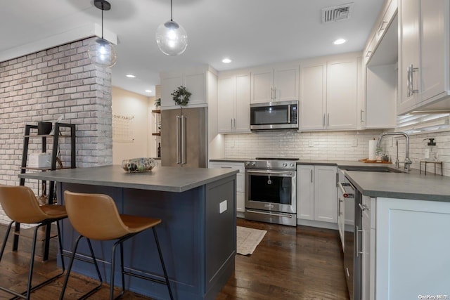 kitchen with white cabinets, decorative light fixtures, stainless steel appliances, and dark wood-type flooring