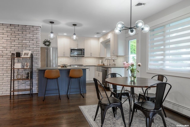 dining room with a baseboard heating unit, sink, dark wood-type flooring, and a chandelier