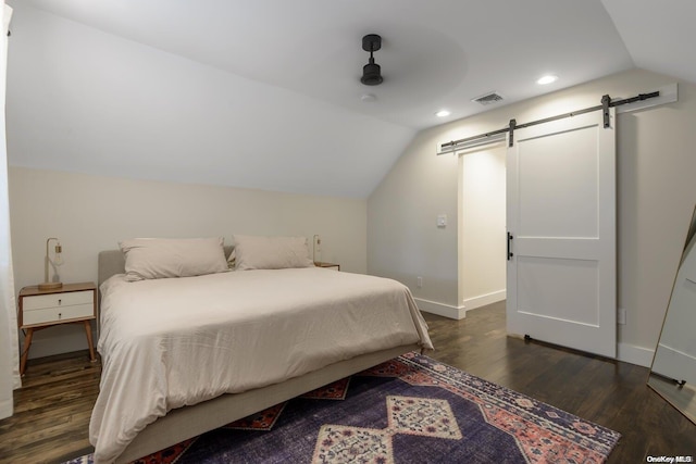 bedroom featuring dark hardwood / wood-style floors, a barn door, lofted ceiling, and ceiling fan