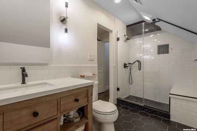 bathroom featuring tile patterned floors, vaulted ceiling, tile walls, toilet, and a shower with shower door