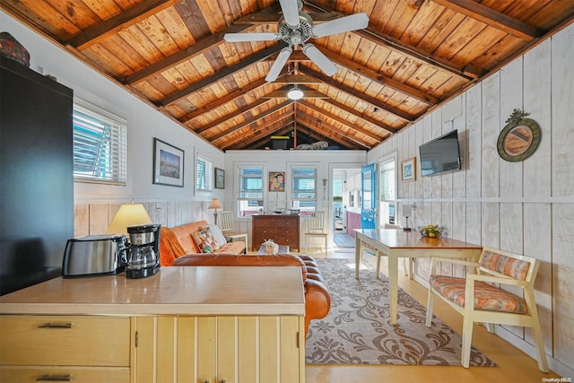 living room with vaulted ceiling with beams, wood walls, ceiling fan, and wood ceiling